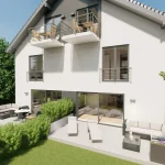 Das Bild zeigt eine moderne Villa am Ammersee mit zwei Stockwerken und mehreren Balkonen. Eine großzügige Terrasse mit Lounge-Möbeln ist im grünen Garten angelegt. Weiß verputzte Wände und eine klassische Dachform dominieren die Architektur.