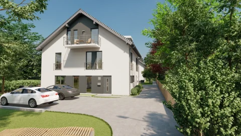 Das Bild zeigt eine moderne Wohnanlage mit zwei weißen Mehrfamilienhäusern, die beide graue Dächer und Balkone haben. Es sind zwei Autos geparkt und der Bereich ist von grünen Bäumen und Sträuchern umgeben. Der Standort könnte in der Nähe des Ammersees sein, wie das Projekt 