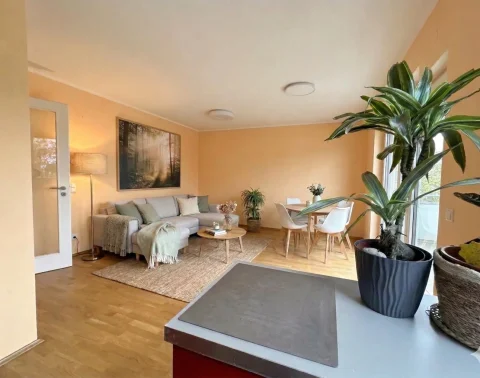 KI Einrichtungsbeispiel moderner Wohn-Essbereich Blick von einer modernen, hellen Küche in einen offenen Wohn- und Essbereich mit stilvollen Möbeln und viel Tageslicht.