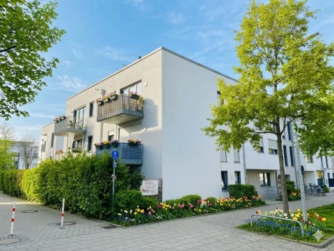 Hausansicht KI optimiert Frühling Immobilienmakler von Goldhaus berät lächelndes Paar an einem modernen Besprechungstisch über Immobilienangebote auf einem Tablet.