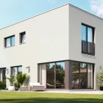 Modernes Einfamilienhaus mit großzügiger Verglasung und Terrasse, umgeben von einem gepflegten Garten. Ideal für den Immobilienmarkt in Buch am Ammersee.