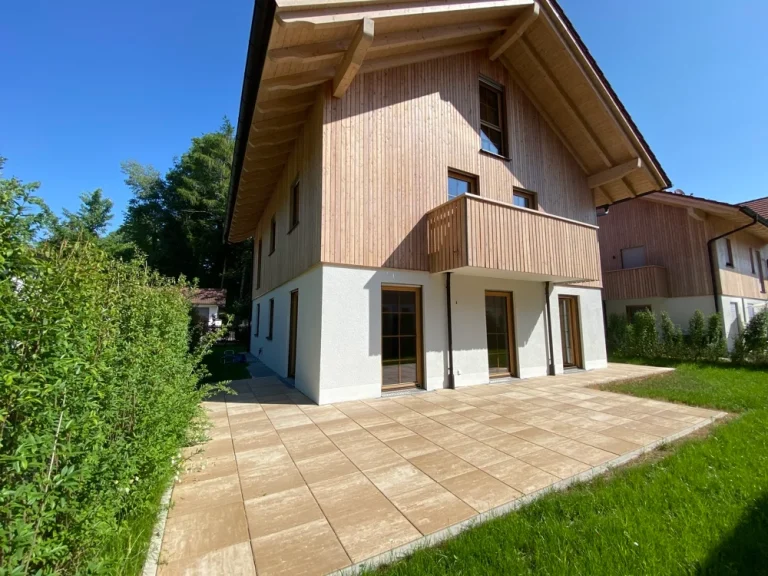 Modernes Einfamilienhaus mit Holzfassade und Terrasse, grüner Garten, im Bereich Ammersee Süd.