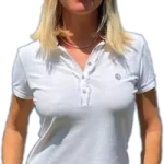 Auf dem Bild Myriam Goldhofer (Immobilienmakler am Ammersee) in einem weißen Poloshirt und dunkler Hose zu sehen. Sie trägt eine Sonnenbrille auf dem Kopf. Ihr Lächeln und ihre entspannte Haltung lassen sie freundlich und professionell wirken. Ihr Outfit ist leger und sommerlich.