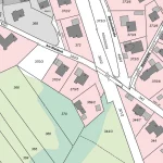 Das Bild zeigt einen detaillierten Katasterplan oder Lageplan. Es sind Parzellen mit Nummern sowie Gebäudestrukturen und Straßen enthalten. Die Straßen „Am Waldeck“ und „Bahnhofstraße“ sind benannt. Der Plan umfasst verschiedenfarbige Bereiche, die unterschiedliche Grundstücksnutzungen oder -eigentümer anzeigen könnten.