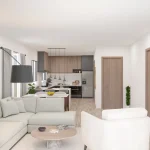 Ein modernes Wohnzimmer mit offener Küche. Es zeigt eine weiße Eckcouch, runde Tische, zwei Gemälde an der Wand und eine Bogenlampe. Die Küche ist mit Holzschränken und integrierten Geräten ausgestattet. Grünpflanzen ergänzen das helle, einladende Ambiente.