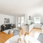 Helles Apartment kombiniert Wohnen und Essen: Sofa, Kunstwerke, Esstisch, moderne Küche mit Kochinsel. Geschmackvolles Interieur mit Holzboden, weiß begin a subtle yet refined aesthetic.