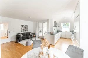 Helles Apartment kombiniert Wohnen und Essen: Sofa, Kunstwerke, Esstisch, moderne Küche mit Kochinsel. Geschmackvolles Interieur mit Holzboden, weiß begin a subtle yet refined aesthetic.