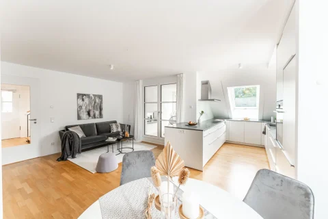 Moderne Wohnküche in hellem Design mit Essbereich Helles Apartment kombiniert Wohnen und Essen: Sofa, Kunstwerke, Esstisch, moderne Küche mit Kochinsel. Geschmackvolles Interieur mit Holzboden, weiß begin a subtle yet refined aesthetic.